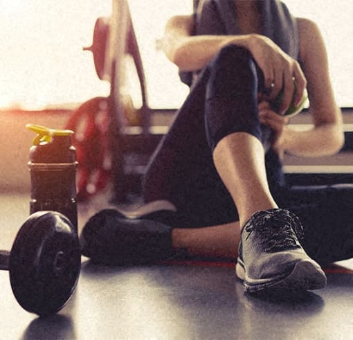 a person sitting on the floor next to a dumbbell and a water bottle